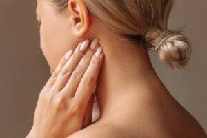 Inflamed tonsillar lymph nodes Young woman touches enlarged lym